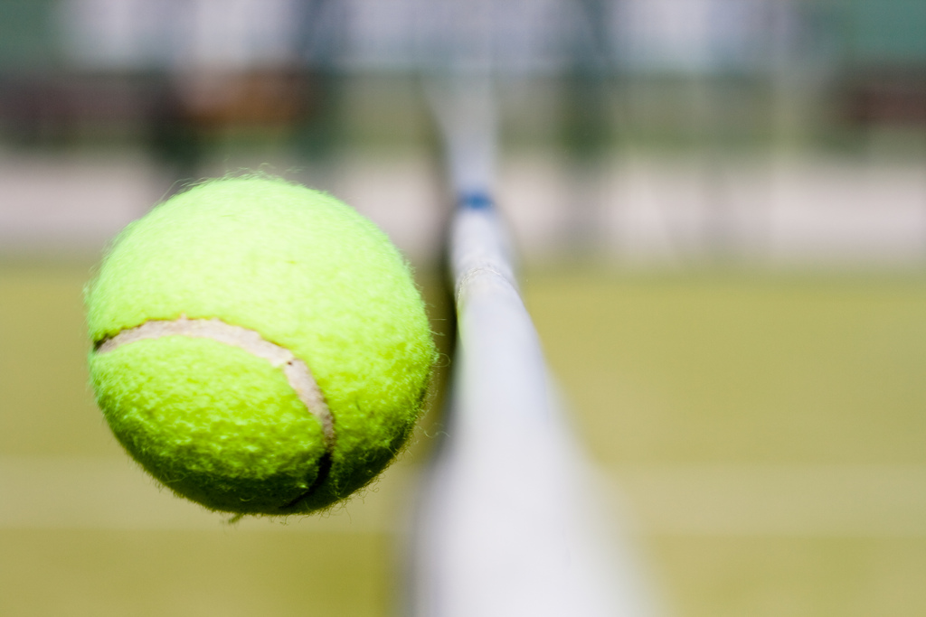 Una pelota de tens que justo está cruzando la red de la pista.
